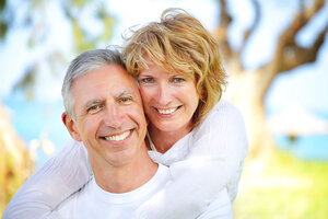 mature older couple smiling outdoors near water dental implants Brooklyn, NY