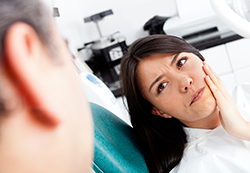 woman holding mouth in pain at dentist root canal Brooklyn, NY